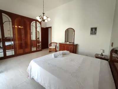 a bedroom with a white bed and a chair at Albachiara in Balestrate