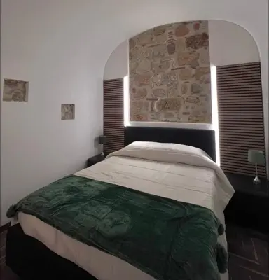 a bedroom with a large bed with a stone wall at Ausa 20 - Tra Storia e Mare in Palermo