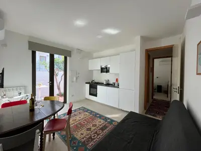 a living room with a table and a kitchen at Giunone Garden in Palermo