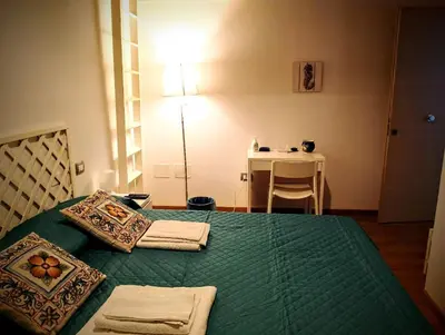 a bedroom with a bed with green sheets and a table at Guest House Lo specchio sul mare in Santa Flavia