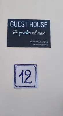 a sign for a guest house on a wall at Guest House Lo specchio sul mare in Santa Flavia