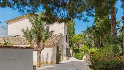 a house with palm trees in front of a driveway at Casale Buccellato 14 by Massimo Villas in Castellammare del Golfo