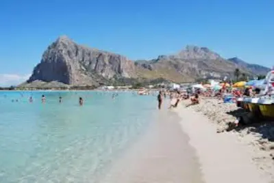 a beach with a bunch of people in the water at Endless summer in Castelluzzo
