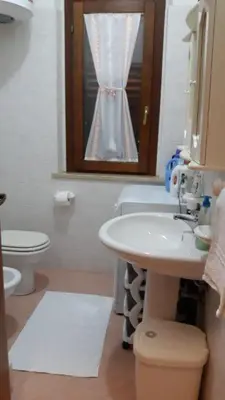 a bathroom with a sink and a toilet and a window at Endless summer in Castelluzzo