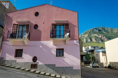 a pink building with windows on a street at Casa Vacanze Cappuccini in Castellammare del Golfo