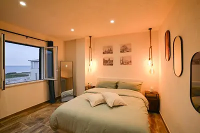 a bedroom with a large bed and a large window at Isula SeaView Apartments in Isola delle Femmine