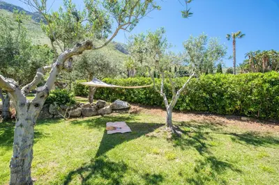 a garden with trees and a hammock in the grass at Ulivo Blu Holiday Homes by Wonderful Italy in Castellammare del Golfo
