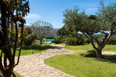 a path through a park with trees and a pool at Ulivo Blu Holiday Homes by Wonderful Italy in Castellammare del Golfo