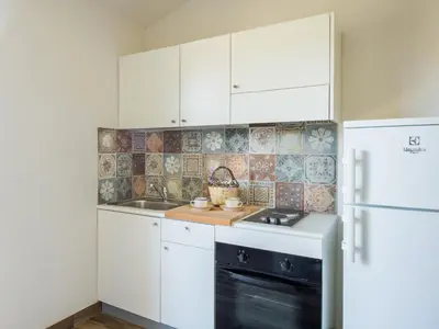 a kitchen with white cabinets and a sink and a refrigerator at Ulivo Blu Holiday Homes by Wonderful Italy in Castellammare del Golfo