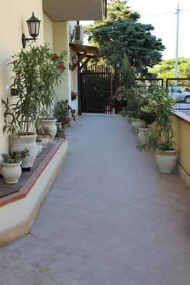 a walkway with potted plants and a black gate at Casa Chiarenza in Castellammare del Golfo