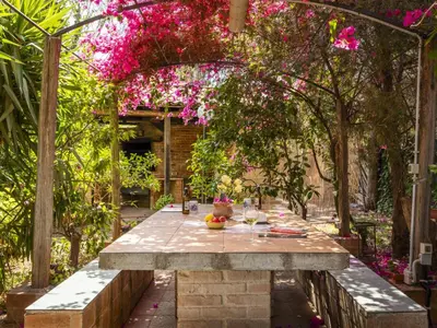 a table in a garden with pink flowers at Apartment Cicladi Naxos by Interhome in Santa Flavia