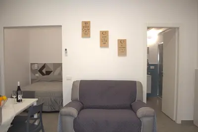 a living room with a chair and a bed at Bom Bom Apartments in Castellammare del Golfo