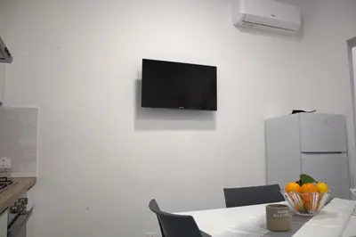 a kitchen with a table with a television on a wall at Bom Bom Apartments in Castellammare del Golfo