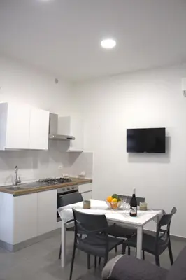 a kitchen with a white table and chairs and a sink at Bom Bom Apartments in Castellammare del Golfo