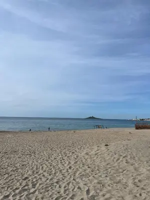 a sandy beach with people in the water and an island at Casa Marina in Isola delle Femmine