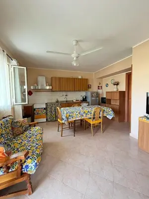 a living room with a table and chairs and a kitchen at Casa Marina in Isola delle Femmine