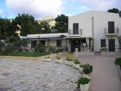 a white building with potted plants in front of it at Baglio Makari in San Vito lo Capo