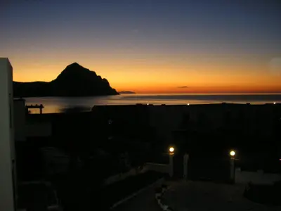 a sunset over the ocean with a mountain in the background at Baglio Makari in San Vito lo Capo