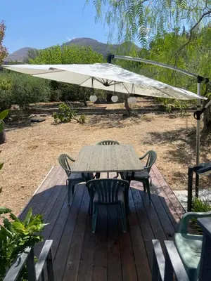 a table and chairs under an umbrella on a deck at Holiday Green in Carini