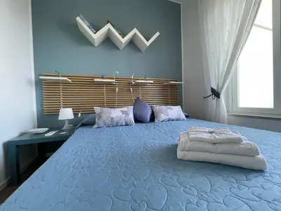 a bedroom with a large blue bed with a desk at Appartanvilla Magellano in Mondello