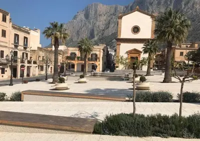 a town with palm trees and a building with a mountain at Da Turiddu in Cinisi