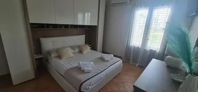 a bedroom with a white bed and a palm tree at I Giardini del mare casa vacanza in Buonfornello