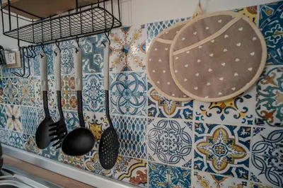 a kitchen with a wall with colorful tiles and utensils at La Casetta di Dandrì in Monreale