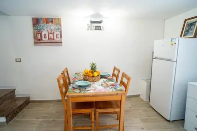 a kitchen with a table with chairs and a white refrigerator at La Casetta di Dandrì in Monreale