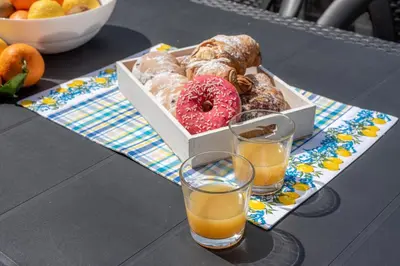 a box of donuts on a table with two glasses of orange juice at Villetta Golfo di Macari 10min San Vito Lo Capo - Horizonte Selections in Castelluzzo