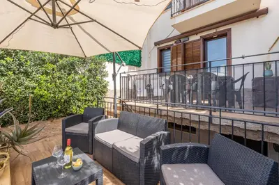 a patio with chairs and an umbrella on a balcony at Villetta Golfo di Macari 10min San Vito Lo Capo - Horizonte Selections in Castelluzzo