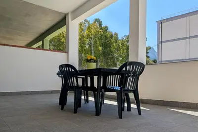 a black dining room table and two chairs on a porch at Nonna Rosa Anna in Isola delle Femmine