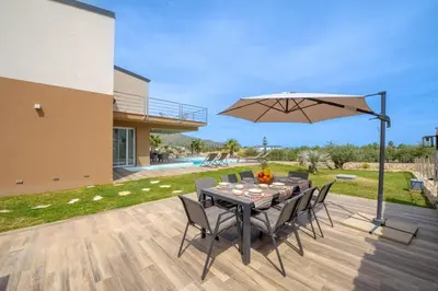 a table with chairs and an umbrella on a patio at Villa Soho in Castellammare del Golfo