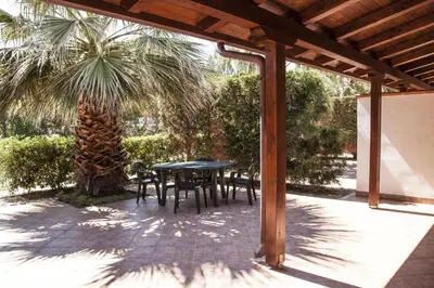 a patio with a table and chairs and a palm tree at Borgomare in Campofelice di Roccella