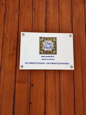 a sign on top of a wooden table at Casa Frufa in Terrasini