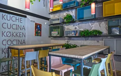 a restaurant with tables and chairs and a wall with plants at Ostello Vucciria in Palermo