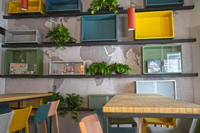a restaurant with tables and plants on the wall at Ostello Vucciria in Palermo