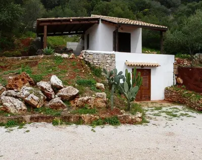 a small white house with a pile of rocks in front of it at Casa panorama in Castelluzzo