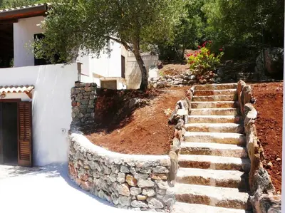 a stone retaining wall and stairs next to a house at Casa panorama in Castelluzzo