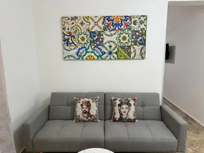 a living room with a couch and a painting on the wall at Beautiful Dimora Anna e Ciccio in Casteldaccia
