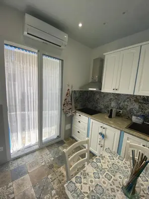 a kitchen with white cabinets and a table and chairs at Sea Diamond in Santa Flavia