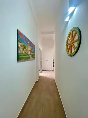 a hallway with white walls and a clock on a wall at Sicilia Bedda Room's in Palermo