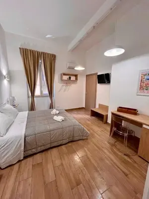 a bedroom with a bed and a desk in it at Sicilia Bedda Room's in Palermo