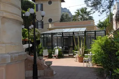 a building with a patio with chairs and a table at Villa 7 Palms Mondello Palermo Sicily in Palermo