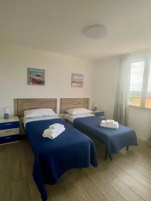 a bedroom with two beds with blue sheets and a window at La Casetta di Gloria in Carini