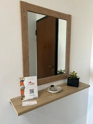 a wooden shelf with a mirror and a book at La Casetta di Gloria in Carini