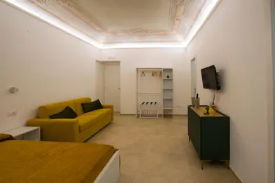 a living room with a yellow couch and a tv at Massimo Rooms and suite in Palermo