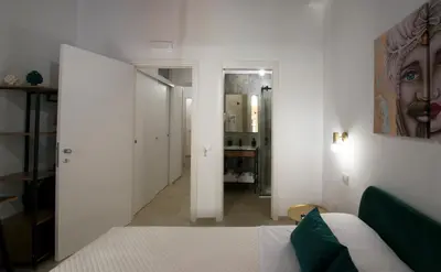 a white bedroom with a bed and a hallway at Massimo Rooms and suite in Palermo