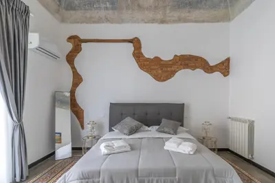 a bedroom with a large bed with a tree branch on the wall at Le Volte Del Basile - 4 camere private e terrazza in Palermo