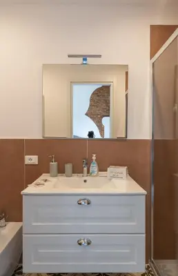 a bathroom with a white sink and a mirror at Le Volte Del Basile - 4 camere private e terrazza in Palermo