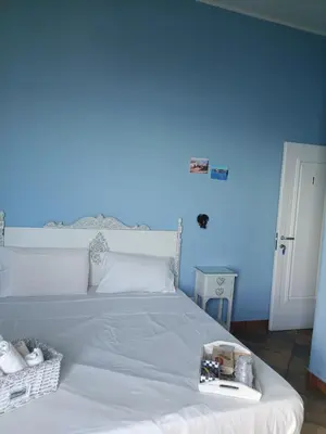 a bedroom with a white bed with a blue wall at Case Nereidi 2 in Porticello